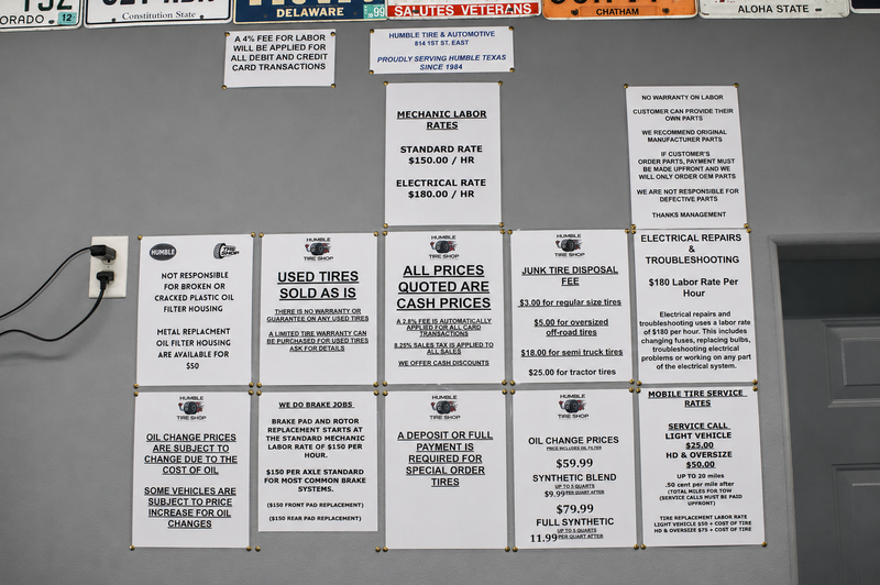 Pricing and policy wall at Humble Tire & Automotive — showing mechanic labor rates, oil change prices, brake job pricing, junk tire disposal fees, and shop policies in Humble, TX